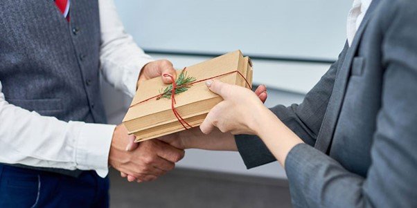 A vendor handing corporate gifts to a client